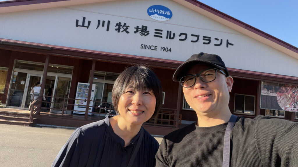 山川牧場ミルクプラントの前で撮影した50代夫婦