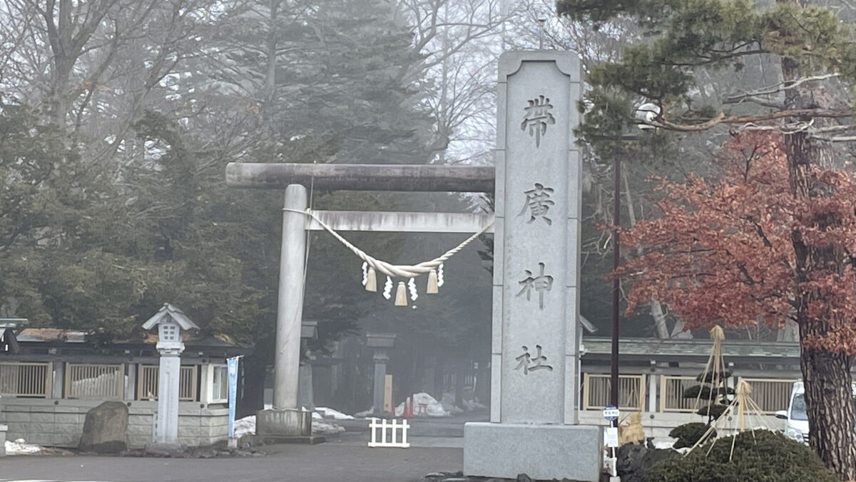 帯廣神社の石柱と雪の残る鳥居、境内へ続く参道